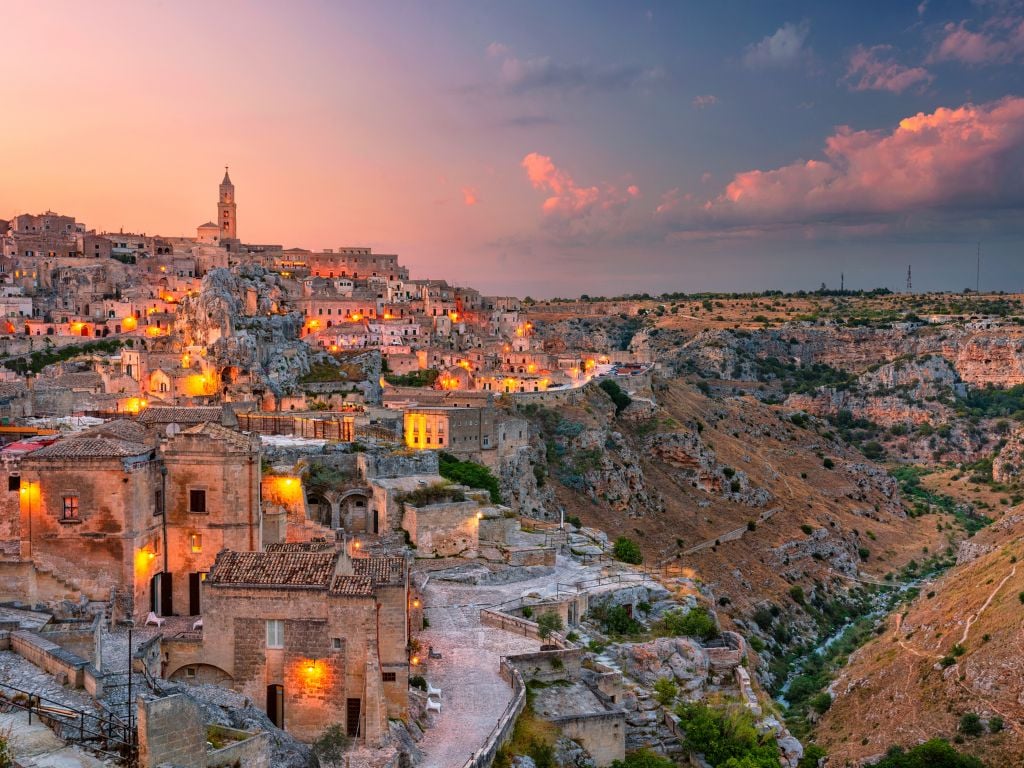 hillside of matera lit up in the early evening