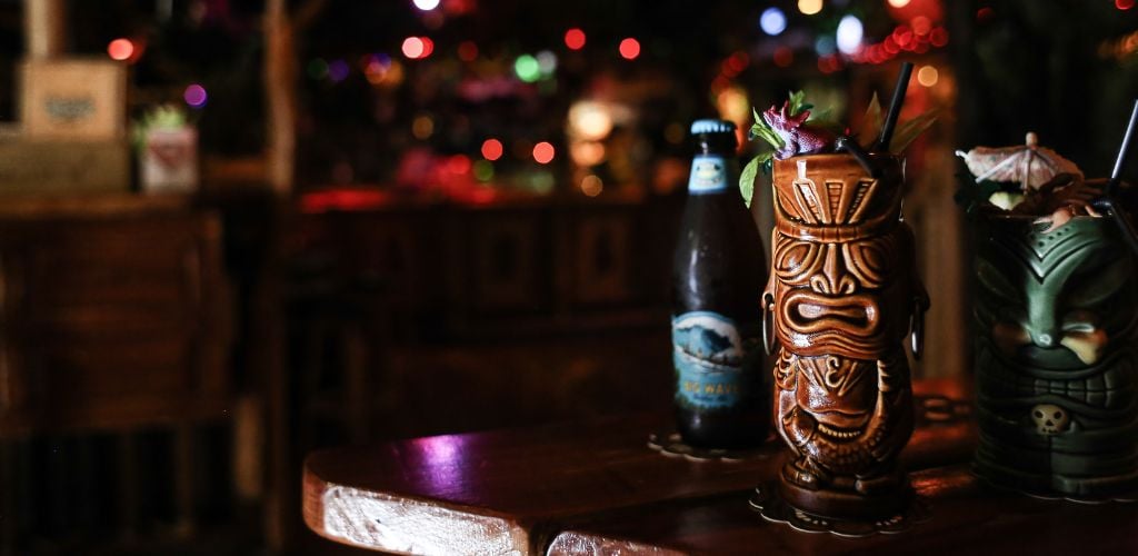 One bottle of beer on the table with two ornate cocktail glasses.