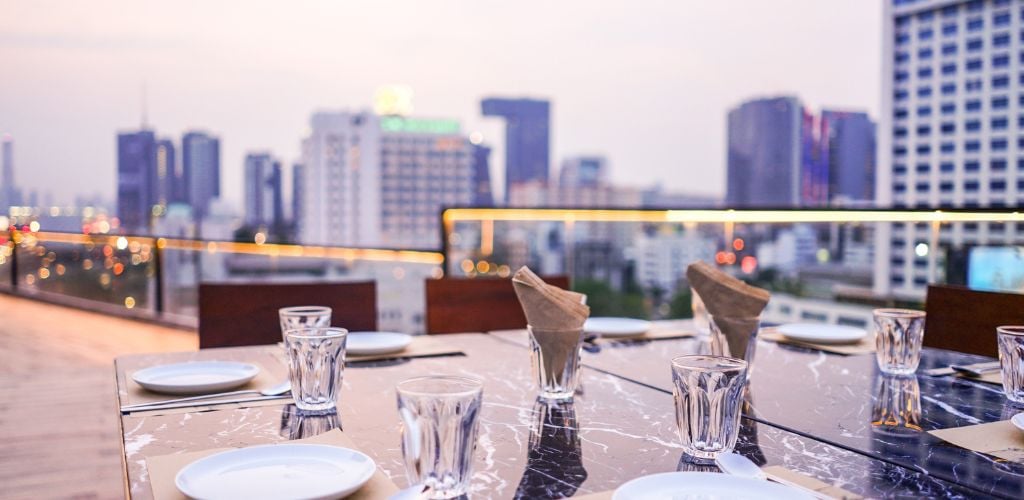 The dining table is set up on a rooftop terrace.