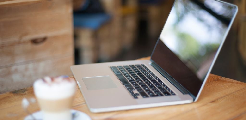 cafe digital nomad set up with laptop and coffee placed on table