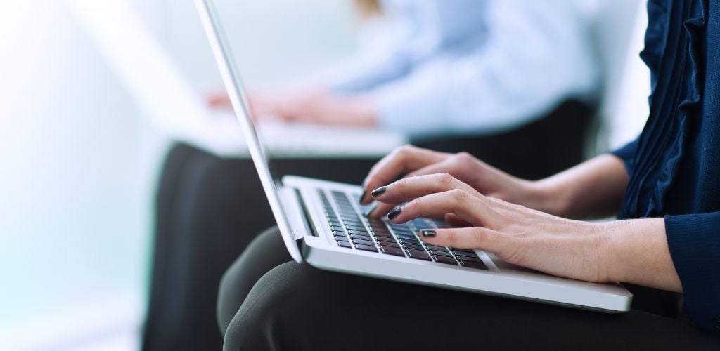 two people working from laptop, sitting with laptops on lap