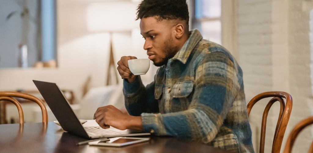 remote worker working from laptop in a homely environment with a coffee mug in hand