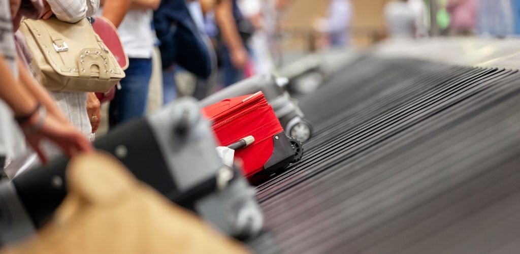 luggage coming around the conveyer belt in an airport. Passengers waiting for luggage around the belt 