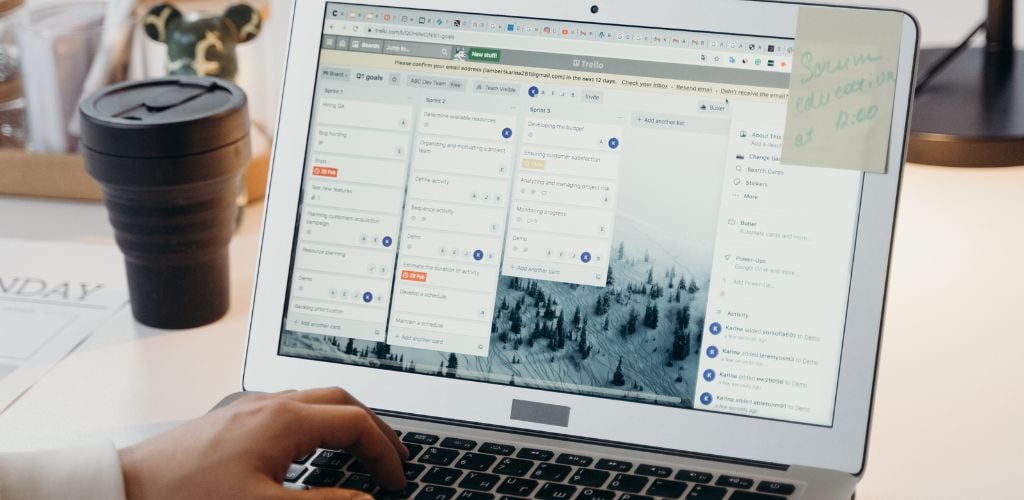open laptop with person typing with one hand, screen is displaying Trello which one of many online project management tools 