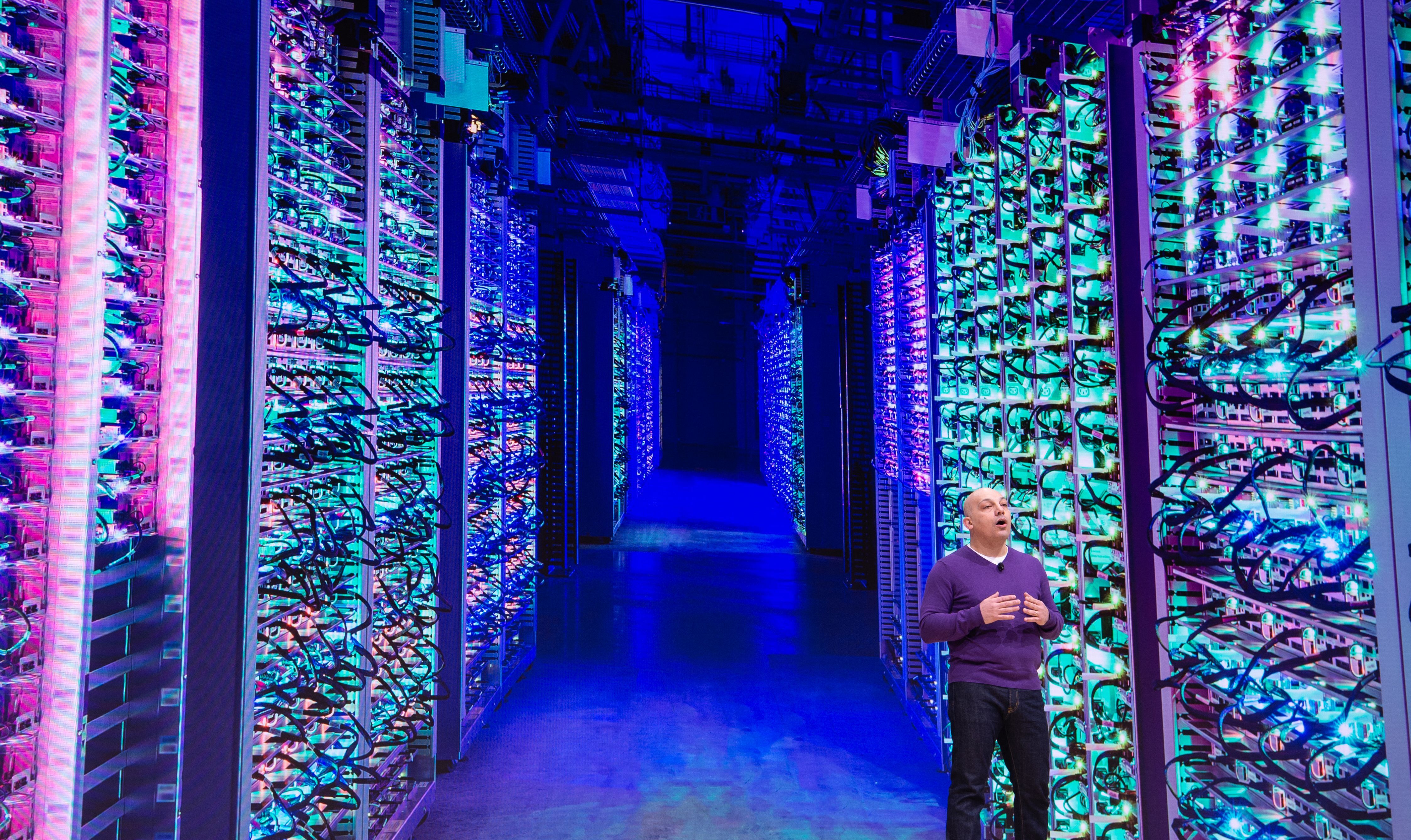 Google Vice President Majd Bakar speaks on-stage during an annual conference in San Francisco with the back drop of a massive data center.