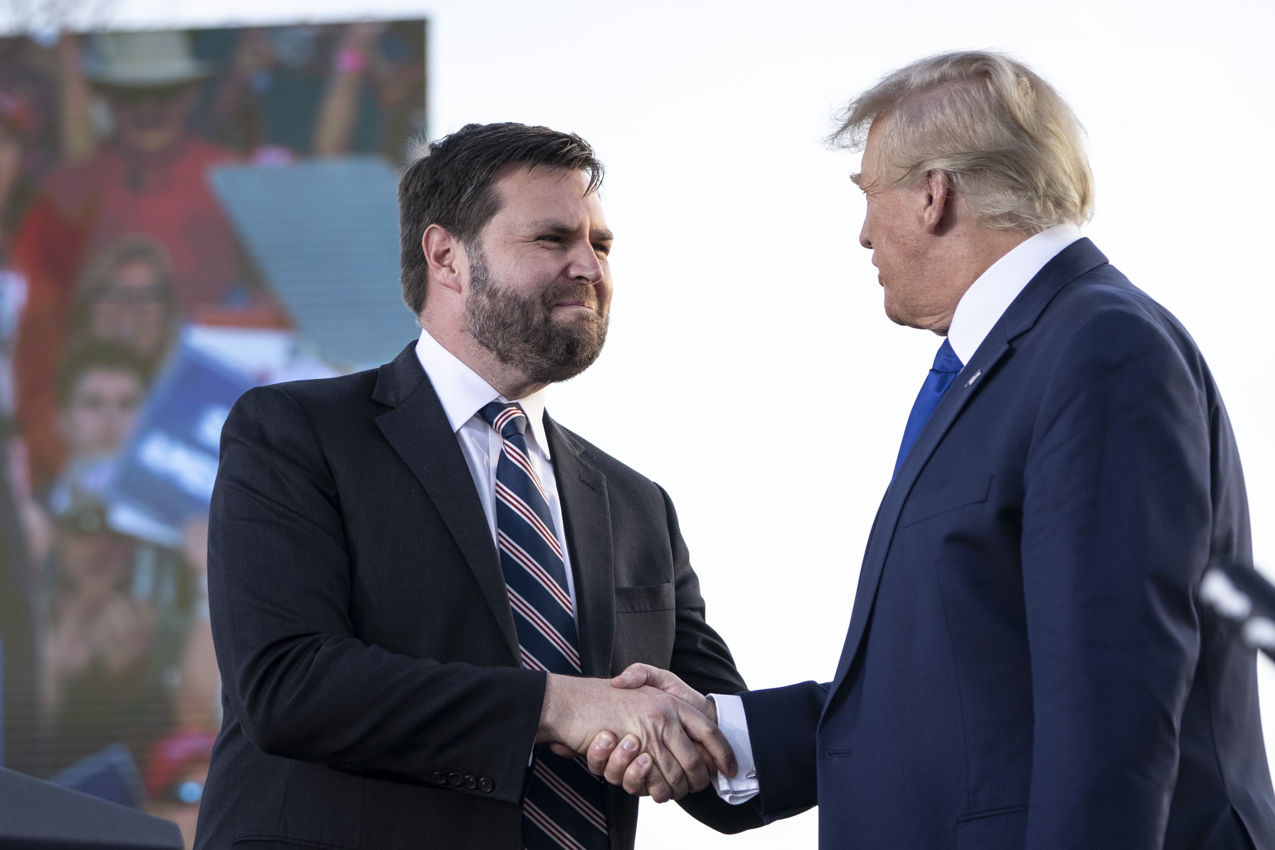 Sen. J.D. Vance of Ohio shakes hands with former President Donald Trump during a rally in Delaware, Ohio in 2023. Vance has ties to tech billionaires who are endorsing his vice presidential nomination.