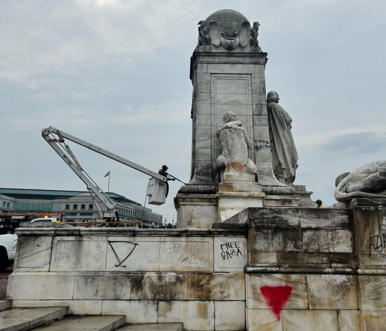 Workers clean graffiti from a statue outside Union Station in Washington, D.C.