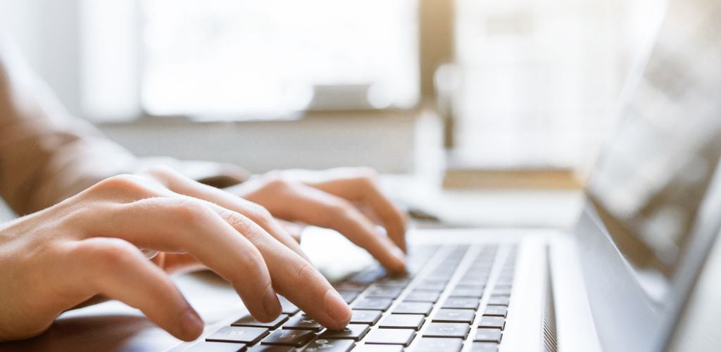 person typing on laptop in home office environment 