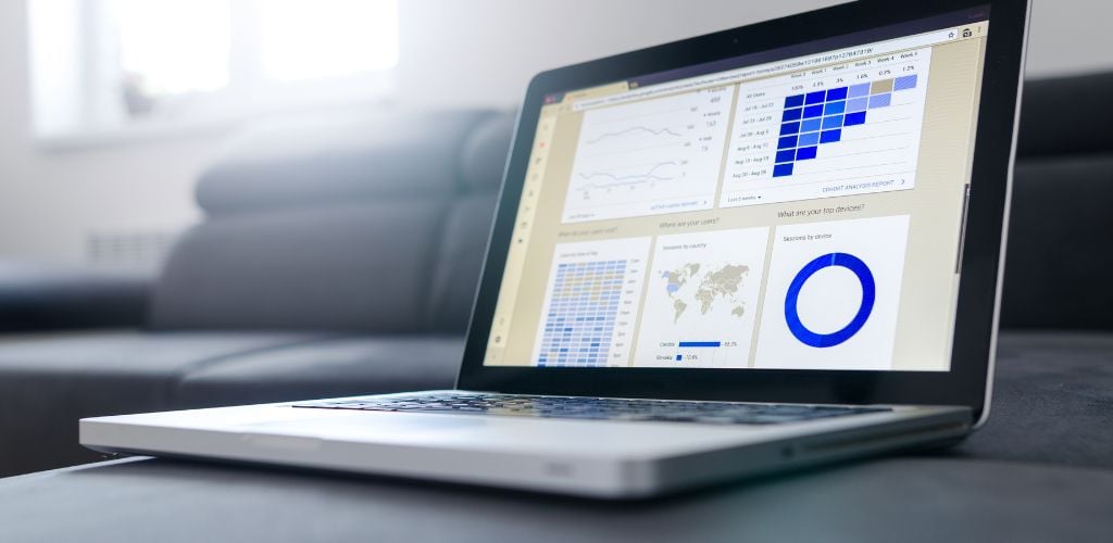 Laptop resting on couch with data and analytics displayed on screen 