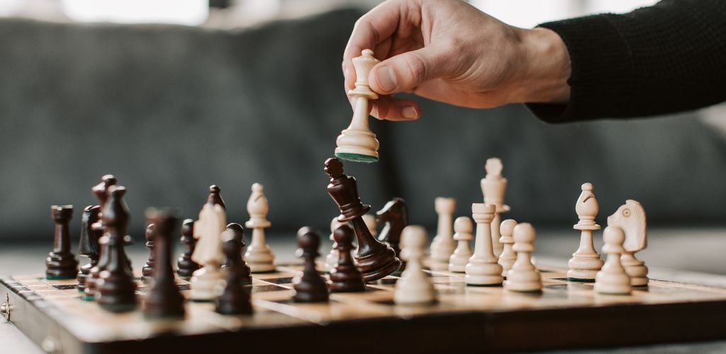 man playing chess, knocking over king of competition 