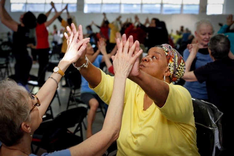 Two women stretch their arms and hands together