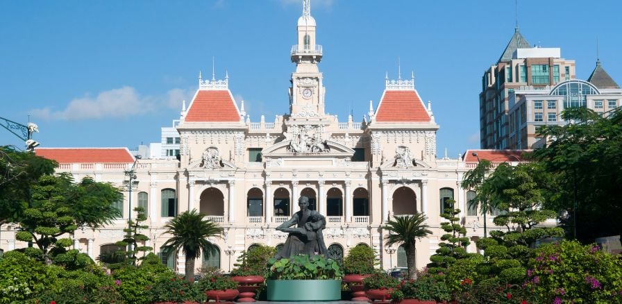 People's Committee Hall Saigon Ho Chi Minh City with statue and trees alongside pathway to main entrance 