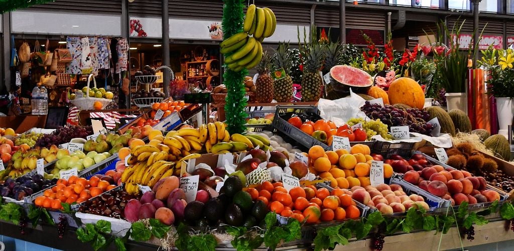 Figueira da Foz Market, market stall selling a range of fresh local fruits including bananas, watermelon, oranges, and grapes.