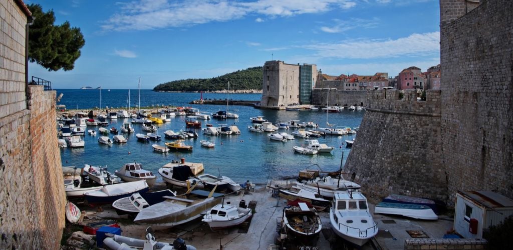 The old port in Dubrovnik, old stone brick walled port with harbour and boats docked and mored