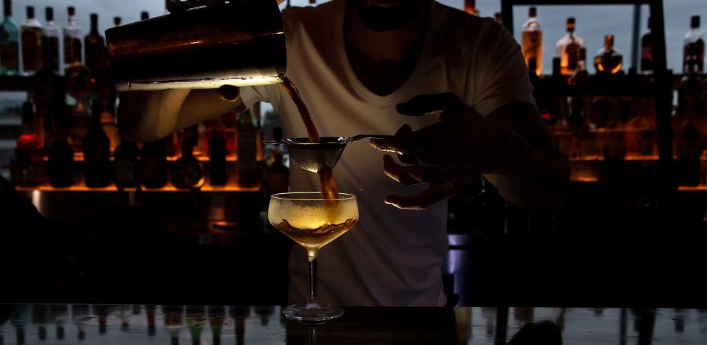 bartender creating a cocktail at a dimly lit bar 