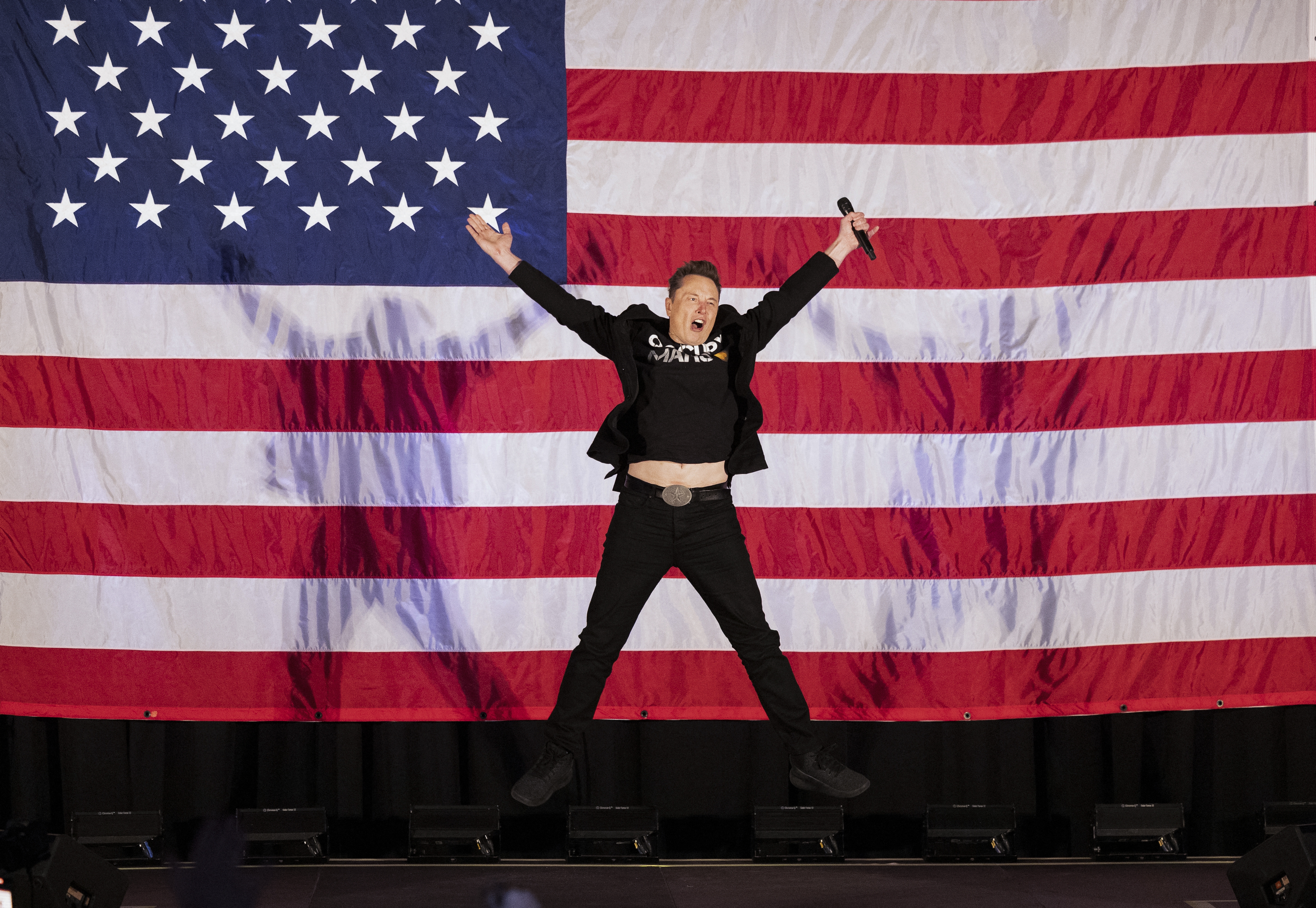 Elon Musk jumps onstage at a town hall event hosted by America PAC in support of Republican presidential candidate Donald Trump in Oaks, Pa., on Oct. 18.