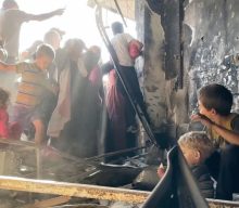 As crowds surge for bread in Gaza, a boy helps his younger brother to drink