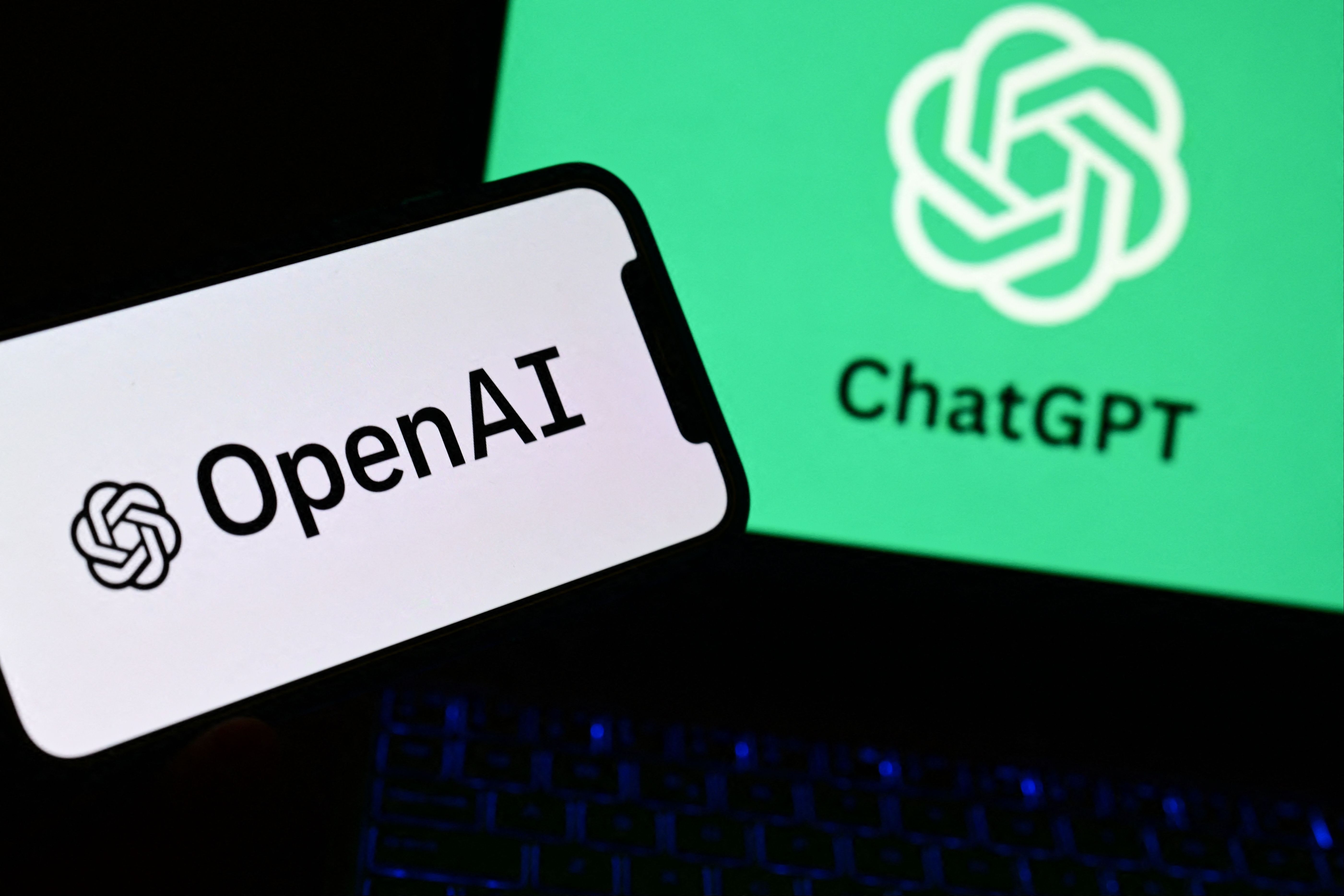 A photo taken on October 4, 2023 in Manta, near Turin, shows a smartphone and a laptop displaying the logos of the artificial intelligence OpenAI research laboratory and ChatGPT robot.