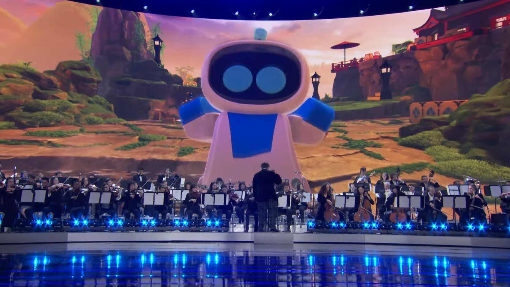 The titular Astro Bot looms over an orchestra playing a medley from the soundtracks to the six Game of the Year nominees.