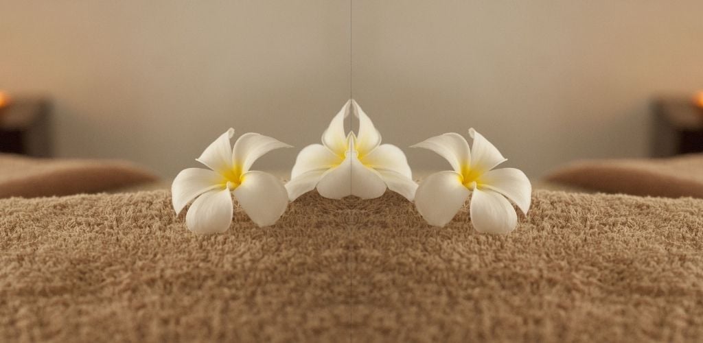 White Flowers at a Spa, mirror image of flowers laid on massage bed and towel 