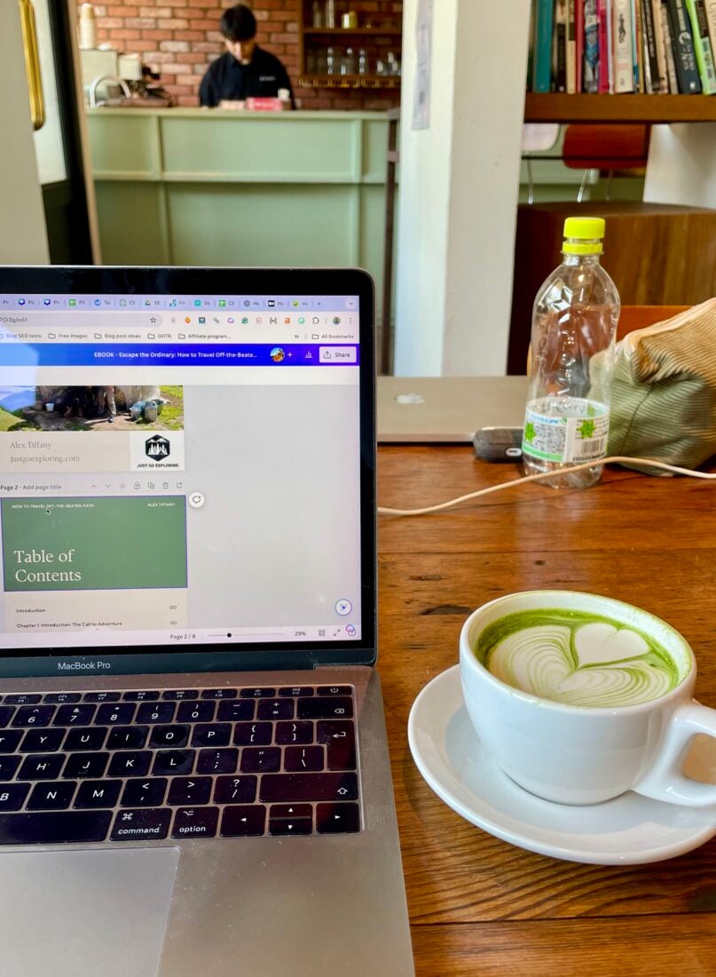 matcha latte on table in a cafe location, open laptop showing website edits on screen